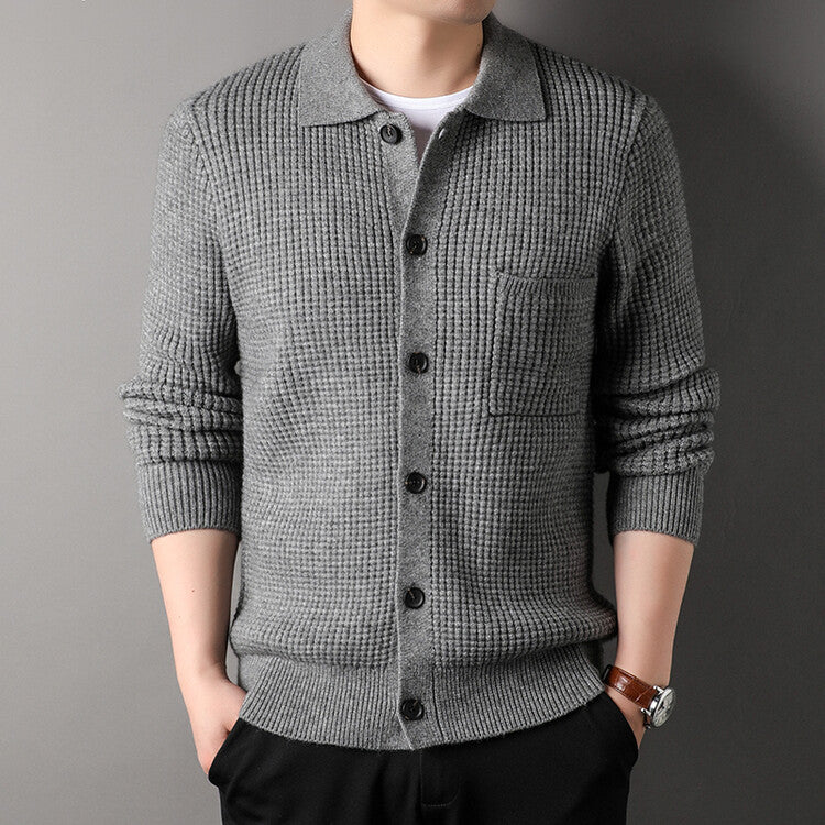 Cardigan uomo grigio in maglia a coste, con bottoni neri e tasca frontale, indossato su camicia bianca. Stile casual elegante, moda autunnale.
