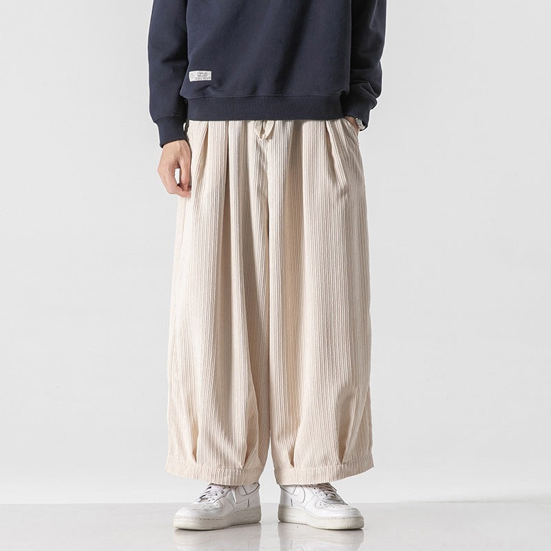 Pantaloni larghi beige a pieghe, indossati con felpa blu e scarpe da ginnastica bianche, moda casual uomo, stile streetwear contemporaneo.
