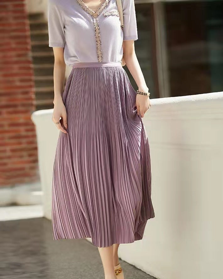 Donna con maglia beige e gonna plissettata viola, moda estiva elegante, abbigliamento casual chic, passeggiata all'aperto, tendenze moda 2023.