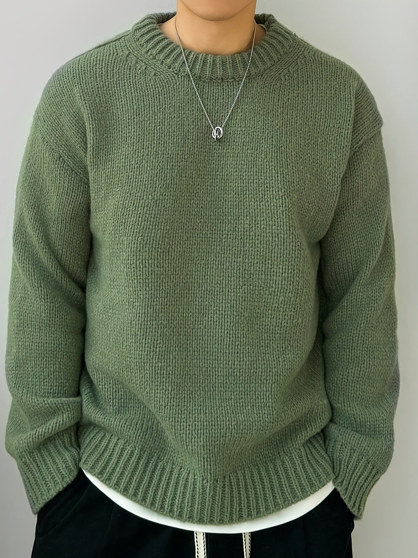 Maglione verde oliva in lana, indossato da una persona, con collana argento. Moda autunnale, abbigliamento casual, stile confortevole.