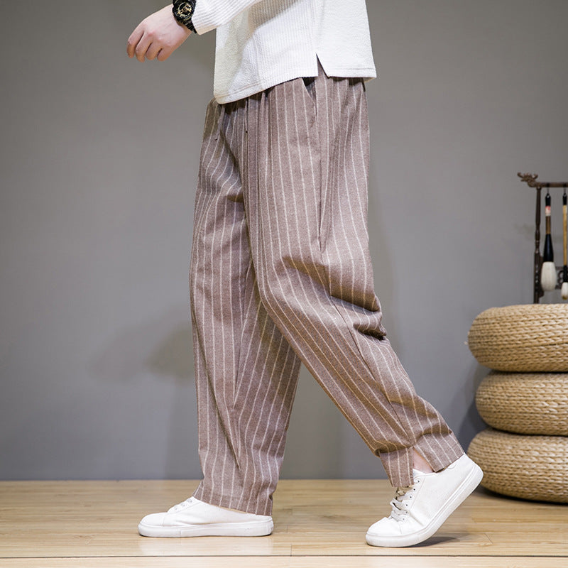 Pantaloni a righe marroni da uomo, stile casual, abbinati a scarpe bianche, su pavimento in legno. Moda maschile, abbigliamento trendy.