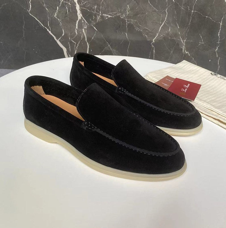 Scarpe mocassini uomo in pelle scamosciata nera su tavolo bianco, sfondo marmo. Eleganti, suola chiara, ideali per look casual e formali.