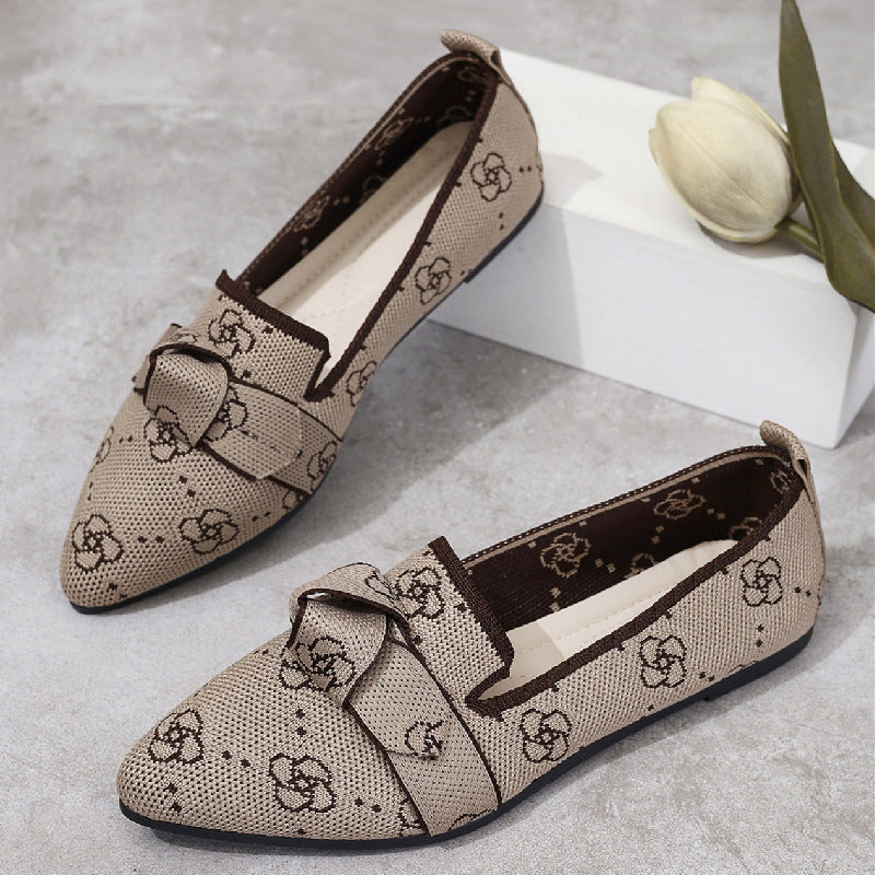 Scarpe mocassino beige con motivo floreale, fiocco decorativo, suola scura, su sfondo grigio con tulipano bianco. Eleganti e alla moda.