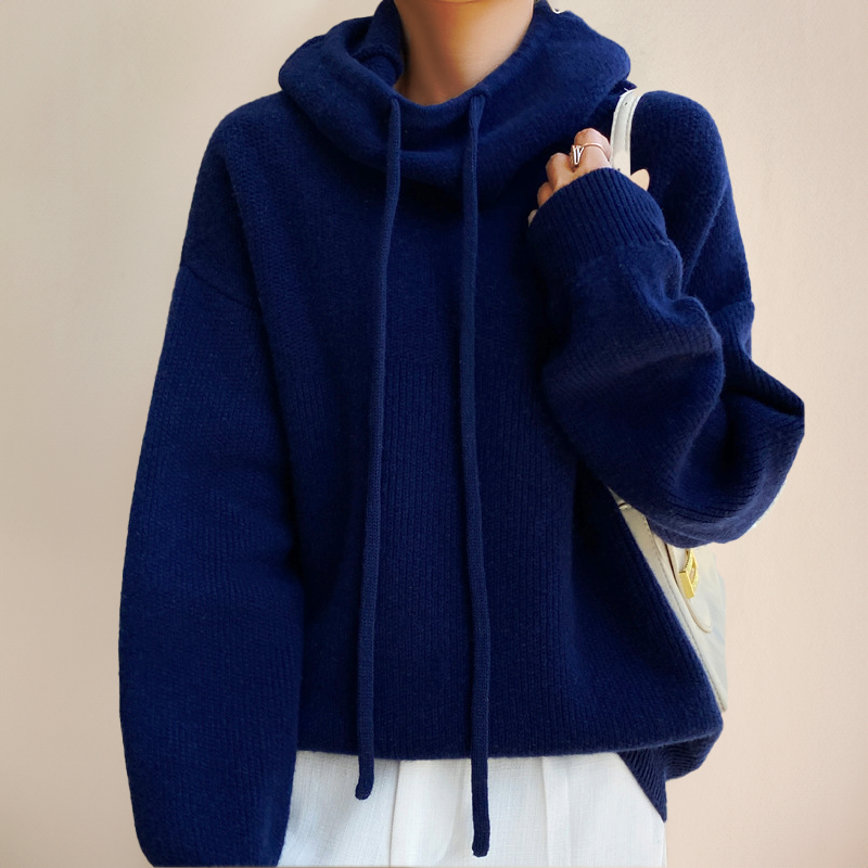 Maglione blu scuro con cappuccio e lacci, indossato da una persona. Stile casual, tessuto morbido, ideale per l'autunno e l'inverno.