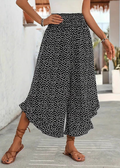 Pantaloni culotte a pois bianchi e neri, indossati con sandali marroni. Moda estiva donna, abbigliamento casual elegante.