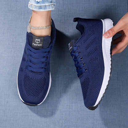 Scarpe da ginnastica blu scuro su sfondo denim, con suola bianca e dettagli in maglia traspirante. Scarpe sportive moda donna, comfort e stile.