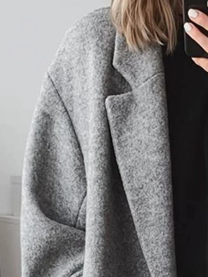Cappotto grigio in lana, stile oversize, indossato da una persona con capelli biondi. Moda autunnale, abbigliamento casual elegante.