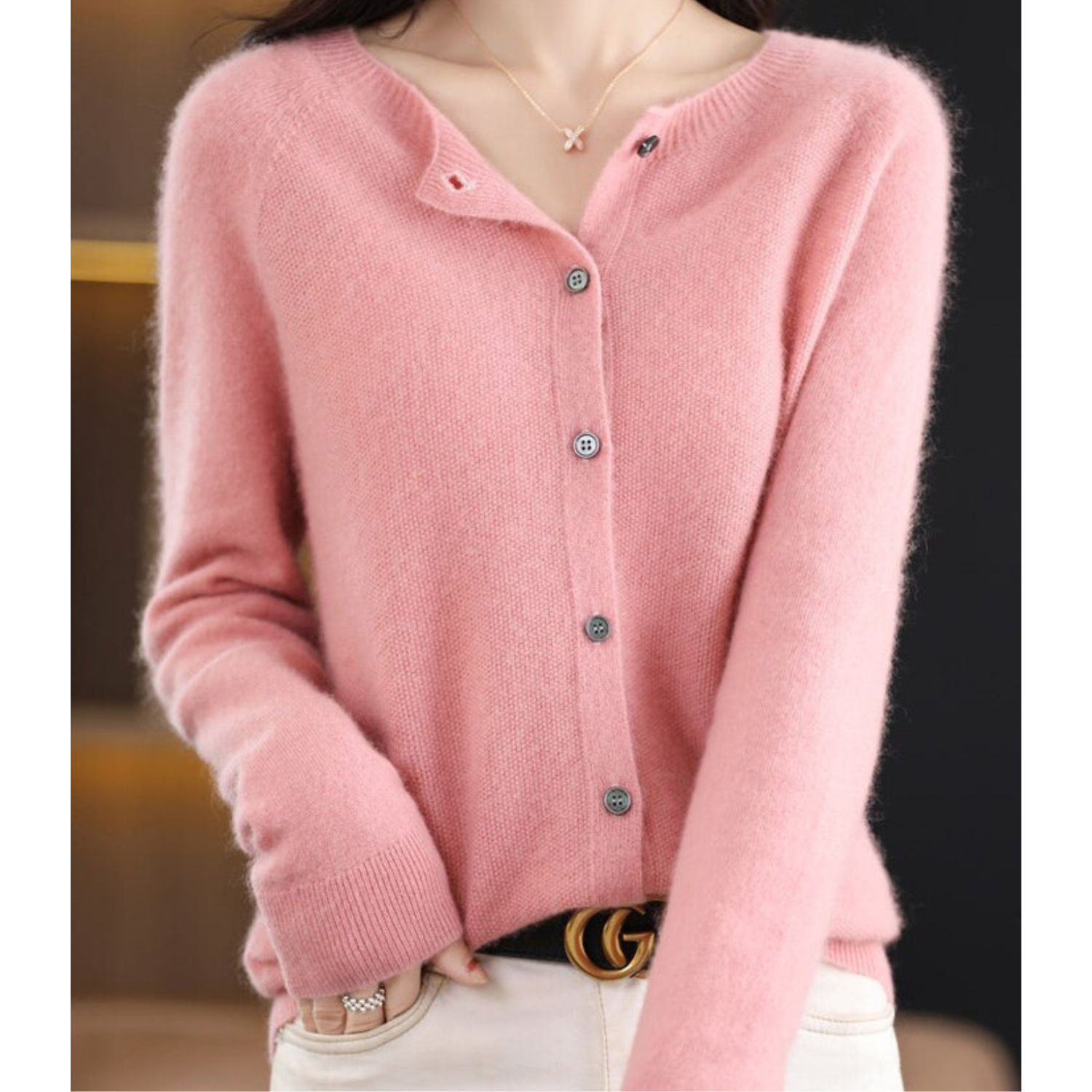 Donna indossa cardigan rosa in cashmere con bottoni, abbinato a pantaloni bianchi. Moda autunnale elegante, stile casual chic.