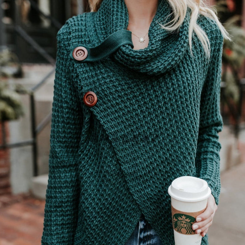 Donna con maglione verde a collo alto e bottoni, tiene un caffè Starbucks. Sfondo urbano sfocato. Moda autunnale, street style.
