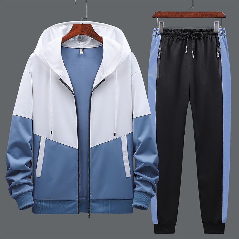 Tuta sportiva uomo, giacca con cappuccio bianca e blu, pantaloni neri con strisce blu, abbigliamento casual, moda fitness, abbigliamento sportivo.
