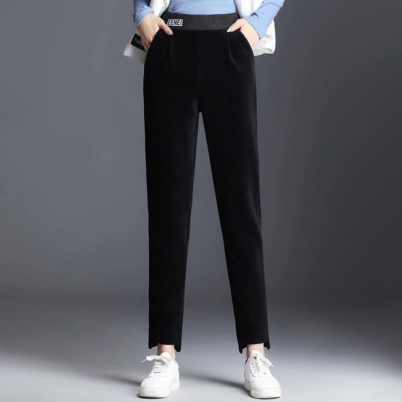 Pantaloni neri a vita alta in velluto a coste, indossati con maglia blu e scarpe bianche. Moda casual donna, abbigliamento autunnale elegante.