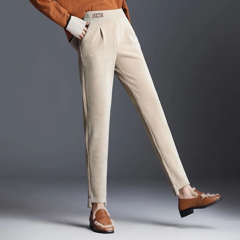 Pantaloni beige a coste in velluto a coste, abbinati a mocassini marroni e maglione arancione. Moda autunnale elegante e casual.