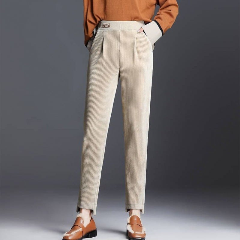 Pantaloni beige a coste, eleganti e moderni, abbinati a scarpe marroni e maglione arancione. Moda autunnale, stile casual chic.