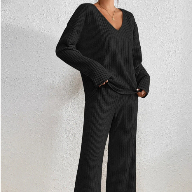 Donna in abbigliamento coordinato nero a coste, maglione e pantaloni larghi, stile casual elegante, sfondo bianco. Moda autunnale donna.