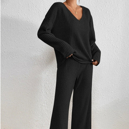 Donna in abbigliamento coordinato nero a coste, maglione e pantaloni larghi, stile casual elegante, sfondo bianco. Moda autunnale donna.