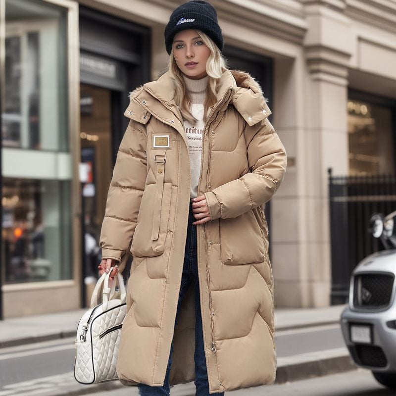 Donna con cappotto lungo beige, borsa bianca trapuntata, cappello nero, in strada cittadina. Moda invernale, abbigliamento casual elegante.