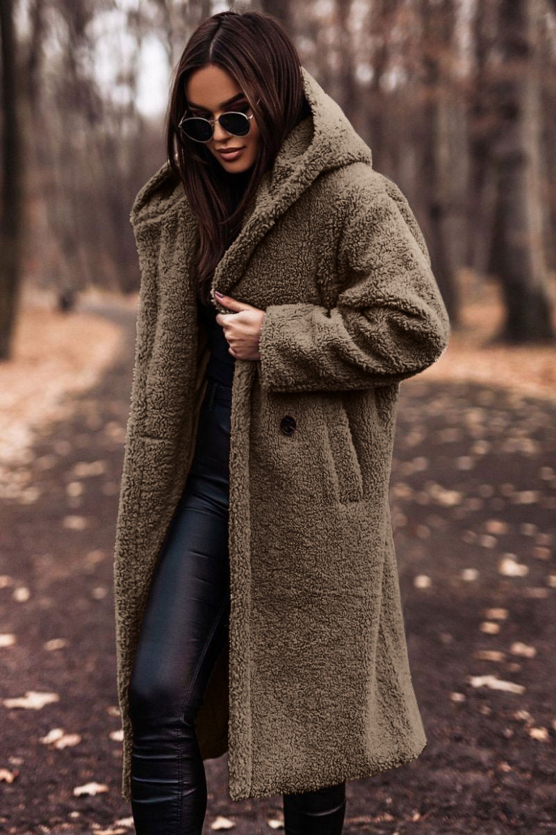 Donna con cappotto teddy marrone, occhiali da sole neri, in un parco autunnale. Moda autunno inverno, stile casual chic, tendenze abbigliamento.