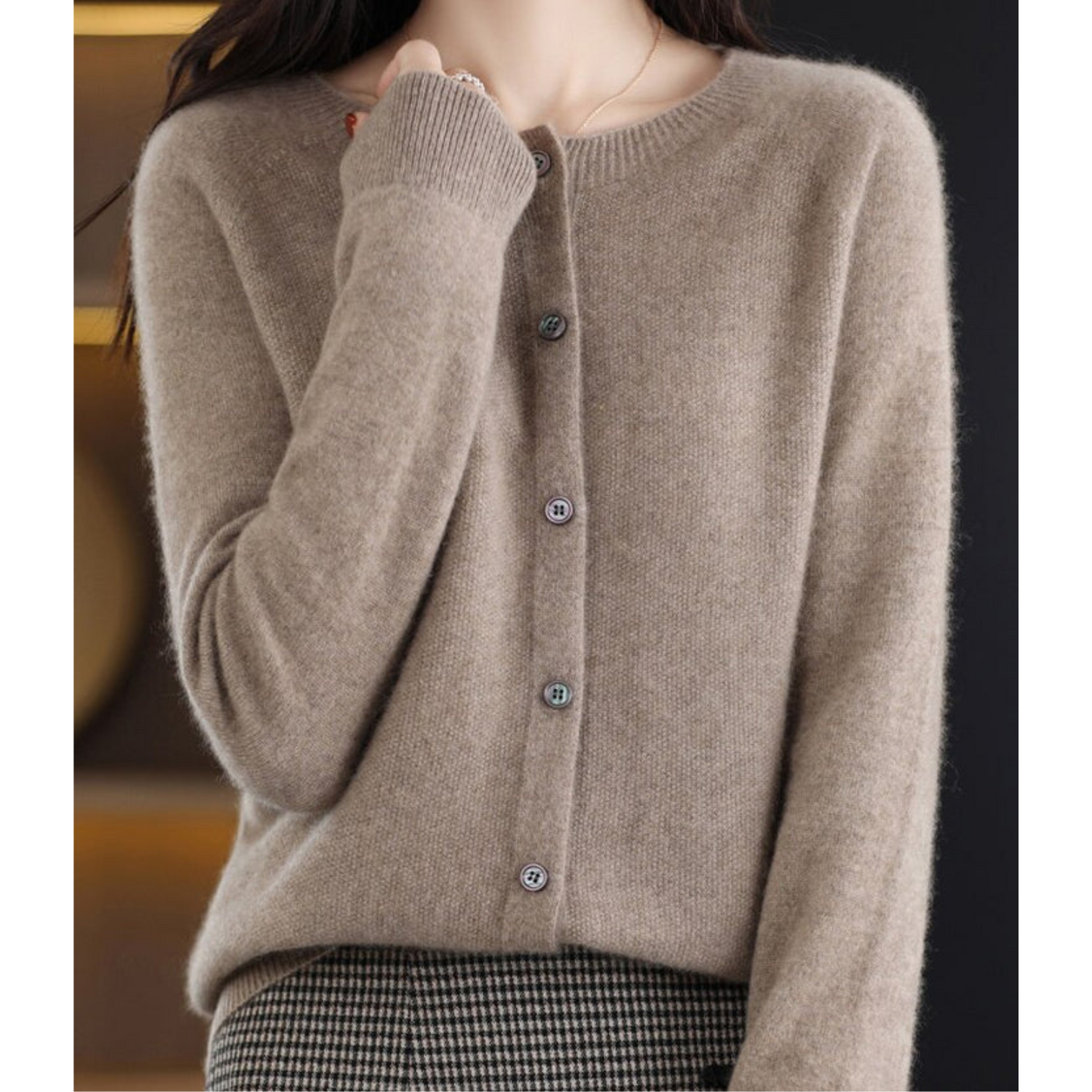 Maglione cardigan beige in cashmere, chiuso con bottoni, indossato da una persona. Stile elegante e caldo, ideale per l'autunno e l'inverno.