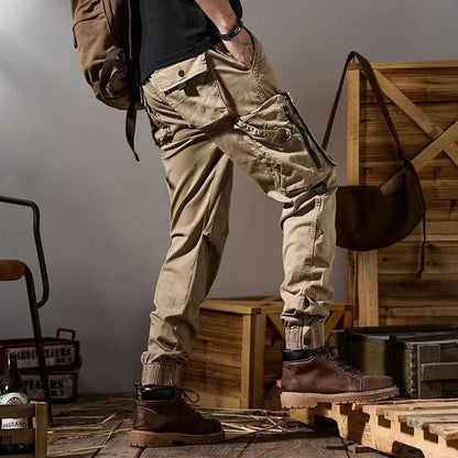 Pantaloni cargo beige da uomo, stile militare, con tasche multiple, abbinati a scarponi marroni. Look casual e robusto per avventure all'aperto.