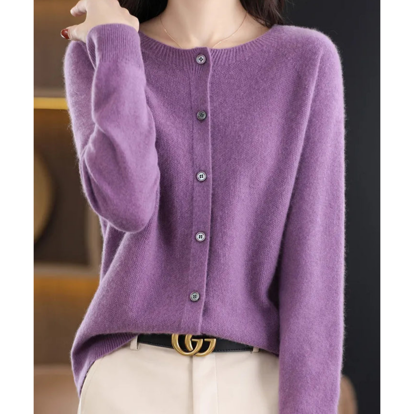 Maglione viola in cashmere con bottoni, indossato da una donna. Elegante e morbido, perfetto per moda autunnale. Cintura nera con fibbia dorata.