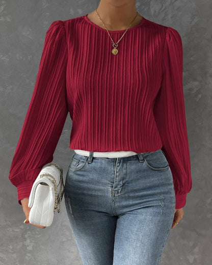 Blusa primaveral de mujer con cuello redondo, mangas largas abullonadas y corte holgado.
