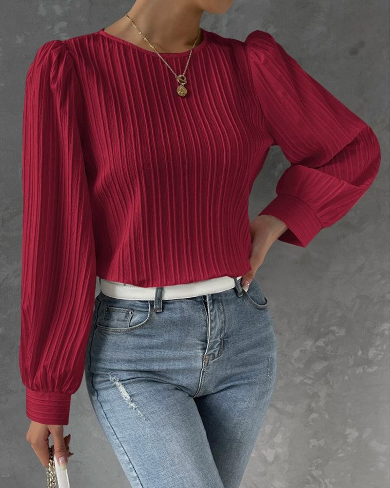 Blusa primaveral de mujer con cuello redondo, mangas largas abullonadas y corte holgado.