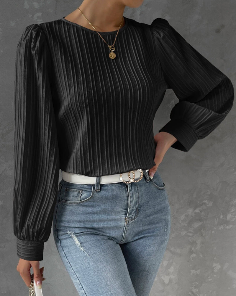 Blusa primaveral de mujer con cuello redondo, mangas largas abullonadas y corte holgado.