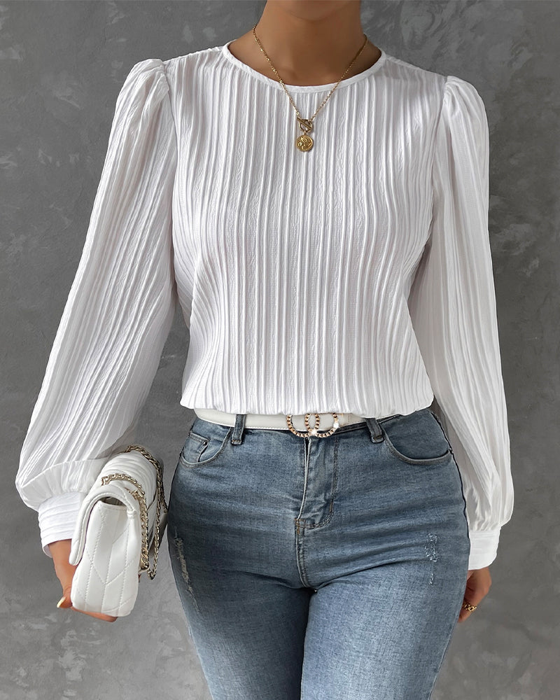Blusa primaveral de mujer con cuello redondo, mangas largas abullonadas y corte holgado.