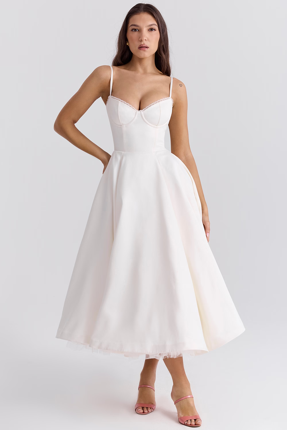 Donna in abito da sposa bianco elegante, lunghezza midi, con spalline sottili e scollo a cuore. Perfetto per matrimoni e cerimonie.