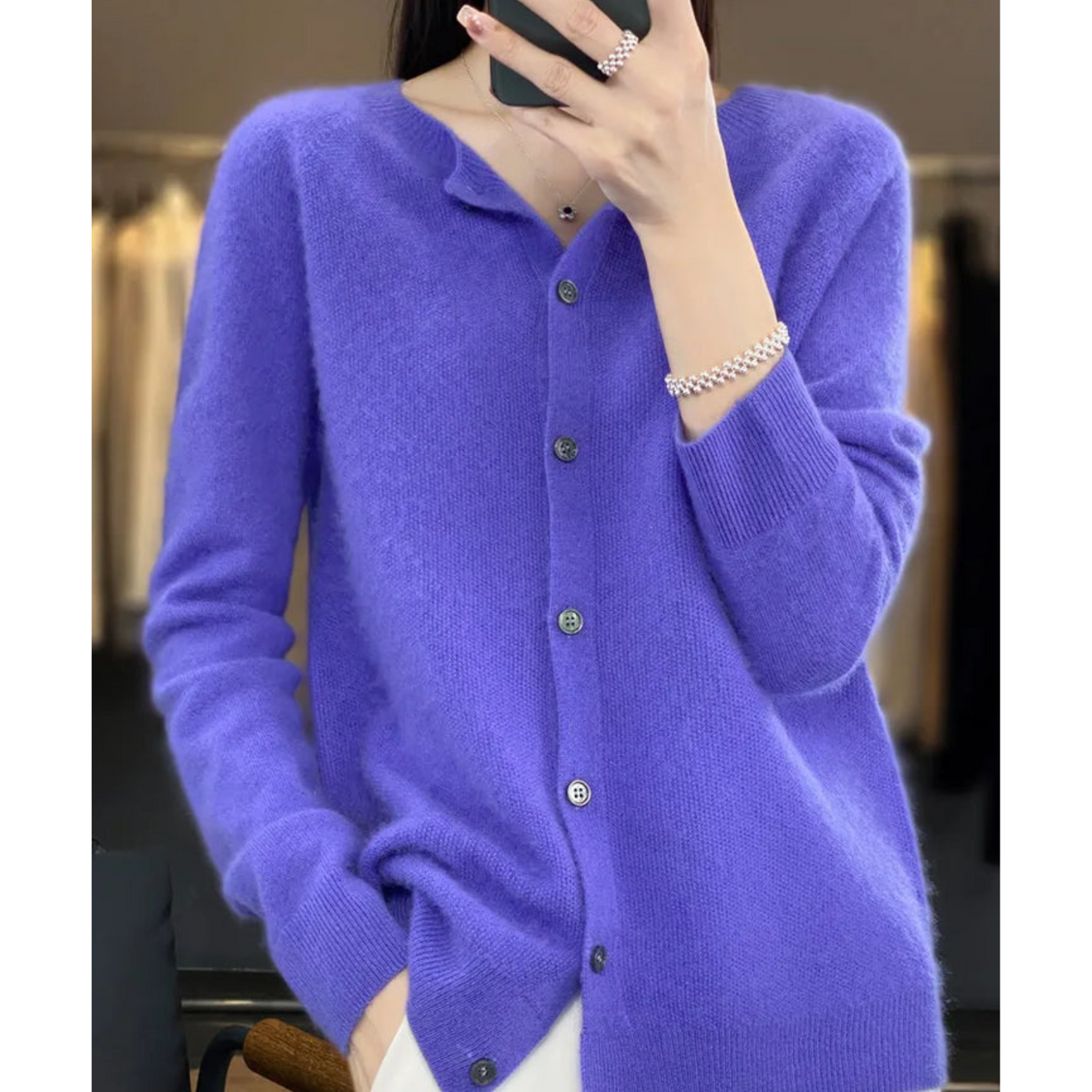 Donna indossa cardigan viola in cashmere con bottoni, abbinato a bracciale argento. Moda autunnale, abbigliamento elegante e confortevole.