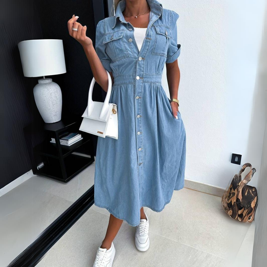 Donna con abito di jeans, borsa bianca e sneakers bianche, in un interno moderno con lampada e decorazioni. Moda casual chic, stile urbano.