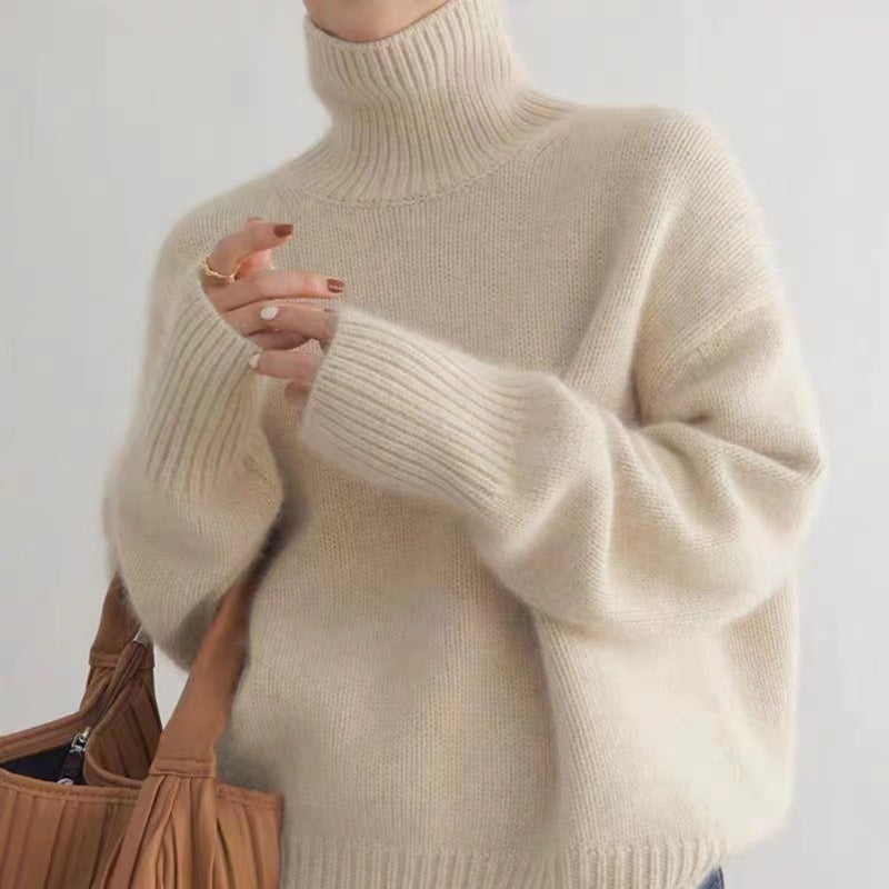 Donna con maglione a collo alto beige, tessuto morbido, tiene una borsa marrone. Moda autunnale, abbigliamento casual elegante.