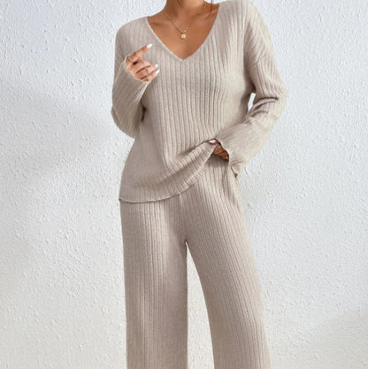 Donna in abbigliamento loungewear beige, maglione e pantaloni a coste, posa contro parete bianca. Moda comoda, stile casual chic.