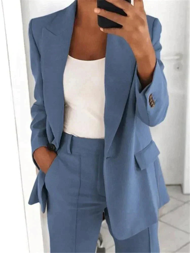 Donna in abito elegante blu, giacca e pantaloni coordinati, con top bianco. Moda femminile, stile business casual, outfit professionale.