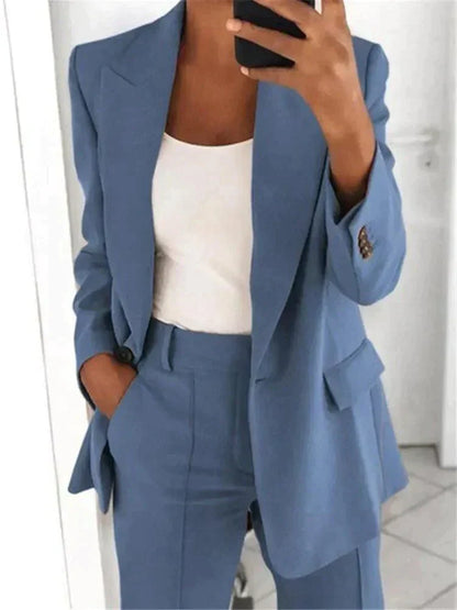 Donna in abito elegante blu, giacca e pantaloni coordinati, con top bianco. Moda femminile, stile business casual, outfit professionale.