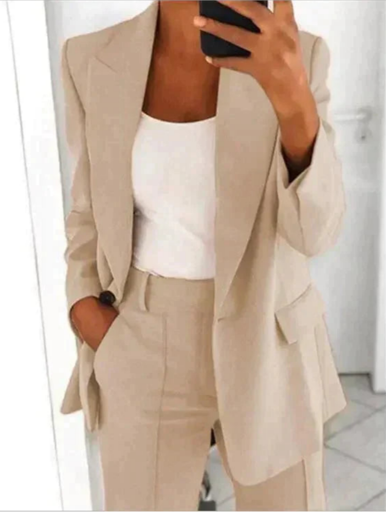 Donna in elegante completo beige, giacca e pantaloni, con top bianco. Moda business casual, outfit professionale, stile minimalista.