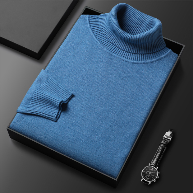 Maglione dolcevita blu piegato in scatola nera su sfondo grigio, accanto a orologio da polso elegante. Moda uomo, abbigliamento invernale.