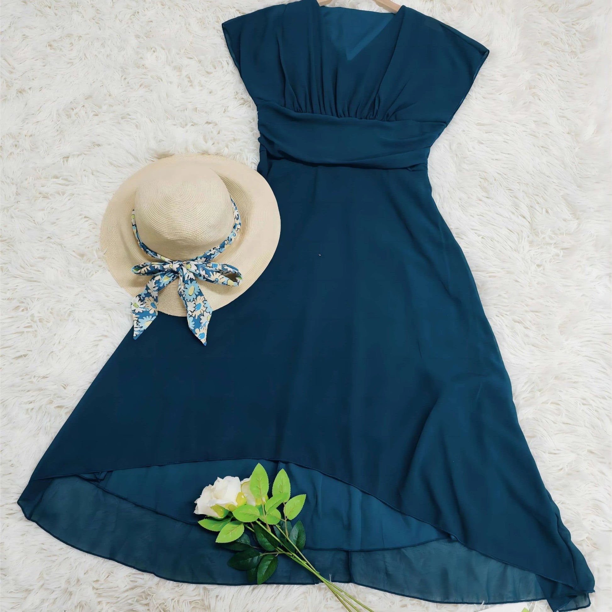 Abito estivo blu elegante su tappeto bianco, accompagnato da cappello di paglia con nastro floreale e rosa bianca. Moda donna, abbigliamento estivo.