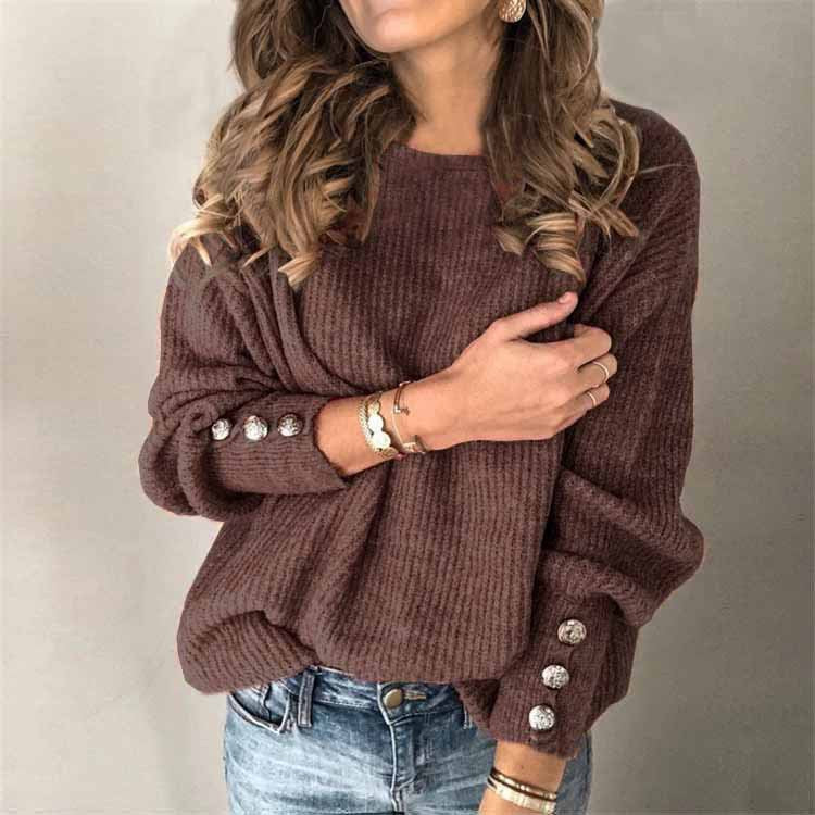 Donna con maglione marrone a coste, bottoni decorativi sulle maniche, indossa jeans e accessori dorati. Moda autunnale casual elegante.