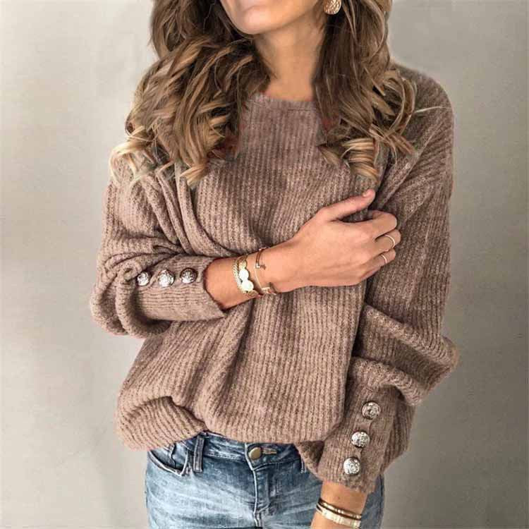 Donna con maglione marrone a coste, maniche con bottoni decorativi, indossa jeans e braccialetti dorati. Moda autunnale casual elegante.