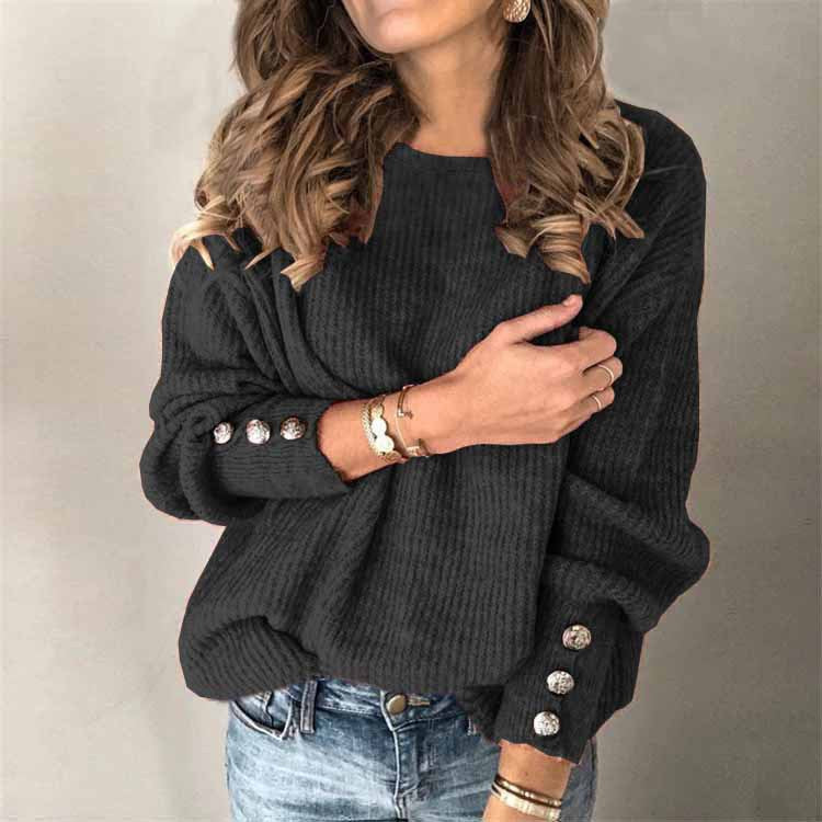 Donna con maglione nero a coste, bottoni decorativi sulle maniche, indossa jeans e accessori dorati. Moda autunnale casual elegante.