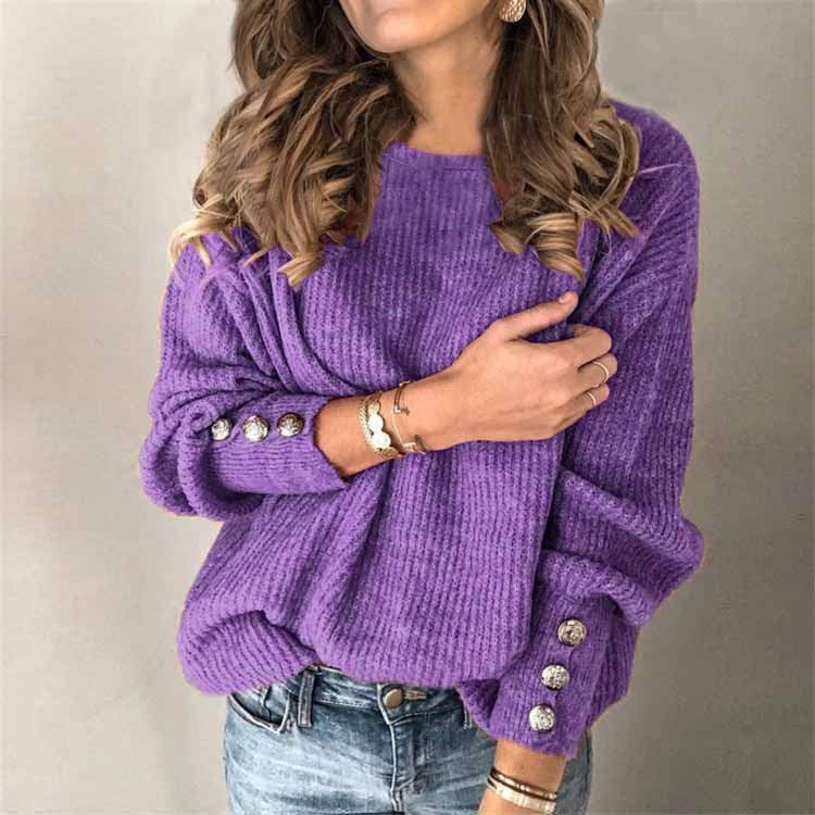 Donna con maglione viola a coste, bottoni decorativi sulle maniche, indossa jeans e braccialetti. Moda autunnale casual elegante.