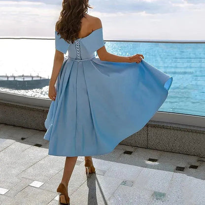 Donna in abito azzurro elegante, spalle scoperte, vista mare. Moda estiva, abbigliamento femminile, abito da sera, look sofisticato.