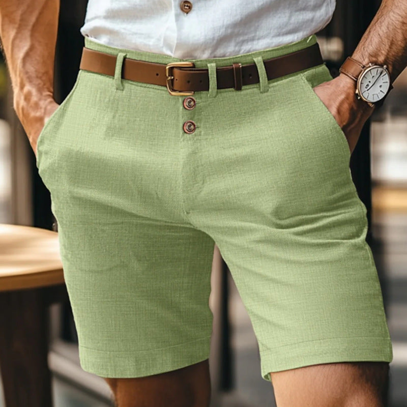 Uomo con pantaloncini verdi eleganti, camicia bianca e cintura marrone. Moda estiva maschile, abbigliamento casual chic.