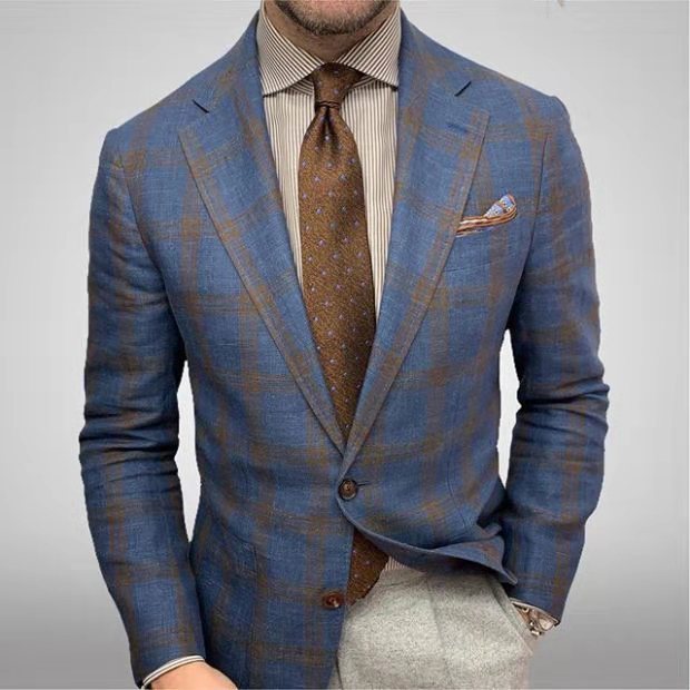 Giacca a quadri blu e marrone su camicia a righe, cravatta marrone, fazzoletto da taschino, moda uomo elegante, abbigliamento formale.