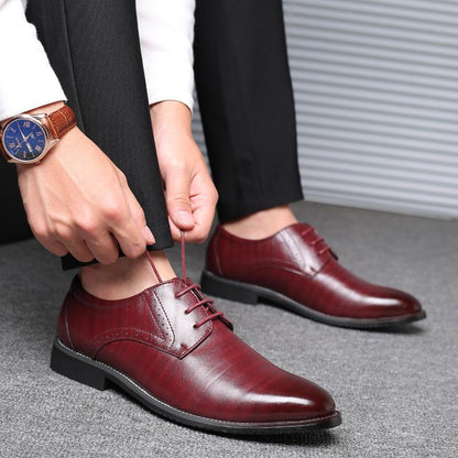 Scarpe eleganti uomo in pelle marrone, indossate con pantaloni neri. Uomo allaccia i lacci, orologio al polso. Moda maschile, calzature formali.