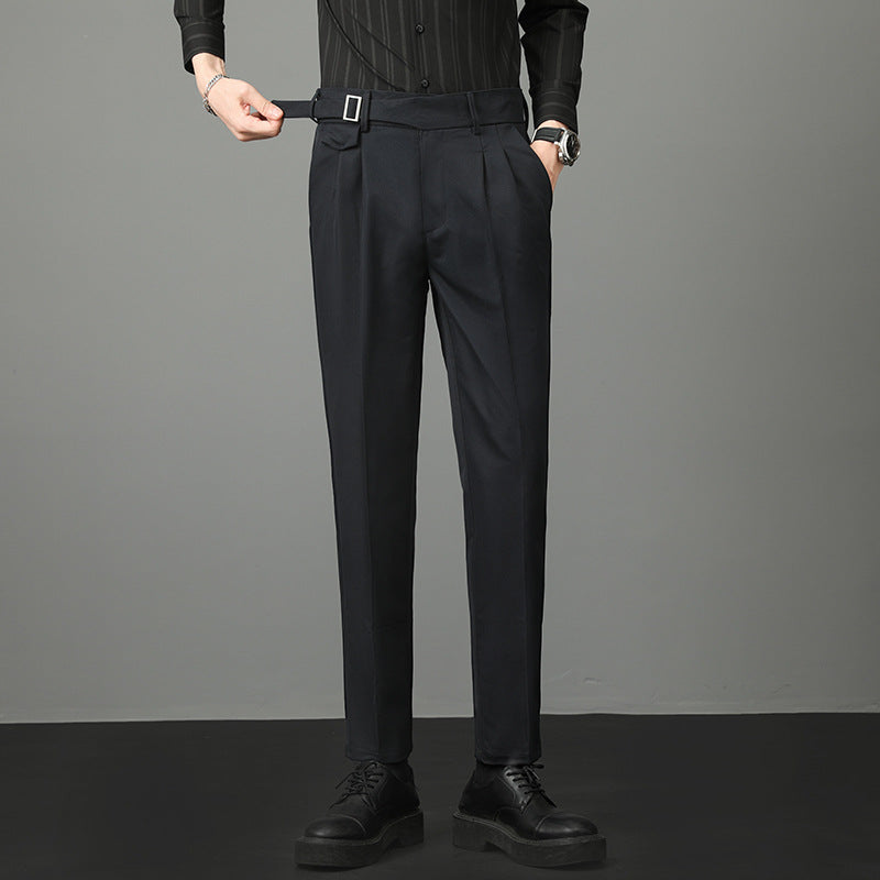 Pantaloni eleganti neri da uomo, con cintura e pieghe, abbinati a camicia nera e scarpe classiche. Moda maschile formale.