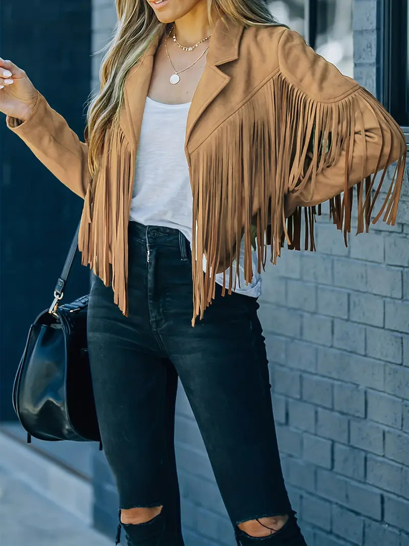 Giacca con frange in pelle scamosciata marrone, indossata con jeans neri strappati e maglietta bianca. Moda autunnale, stile casual chic.