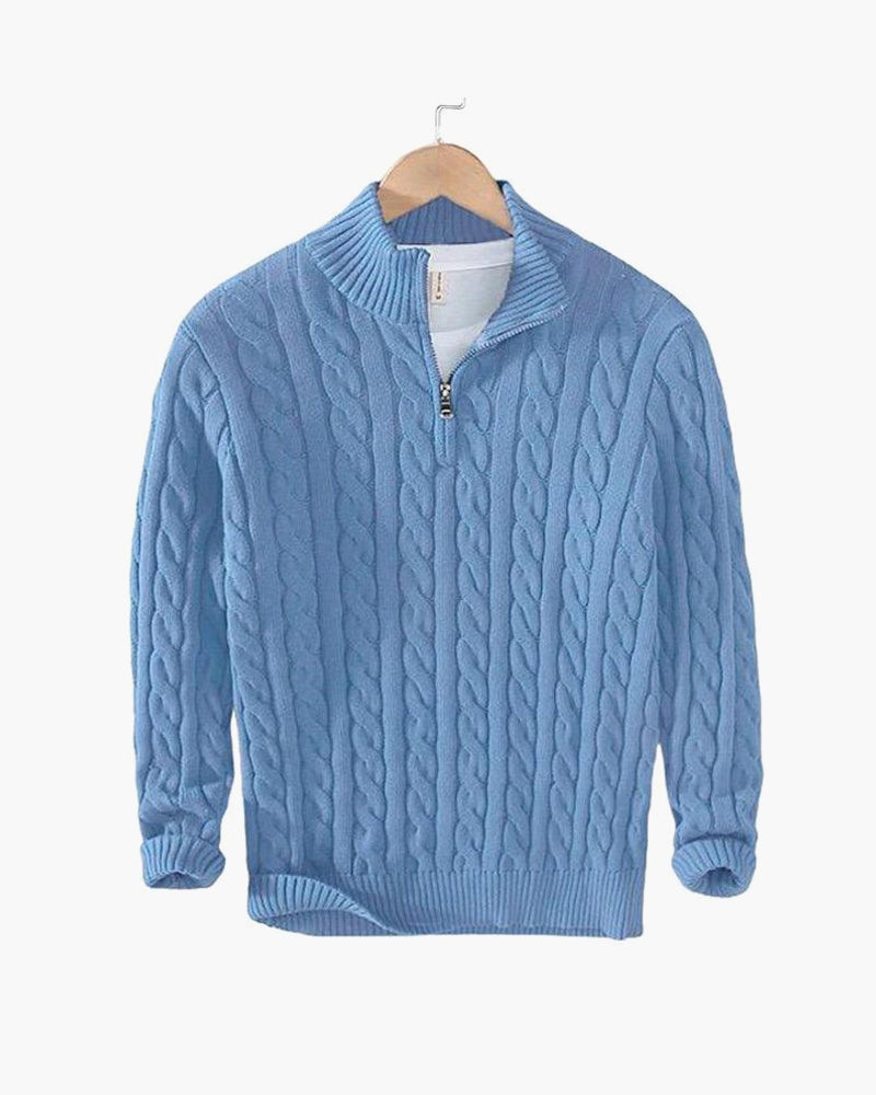 Maglione azzurro in lana con zip, motivo a trecce, appeso su gruccia di legno. Maglione caldo, moda autunno inverno, abbigliamento casual elegante.