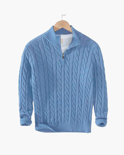 Maglione azzurro in lana con zip, motivo a trecce, appeso su gruccia di legno. Maglione caldo, moda autunno inverno, abbigliamento casual elegante.